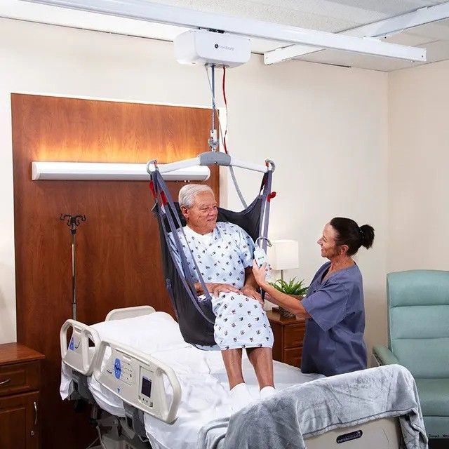 A man is being lifted in a hospital bed by a nurse