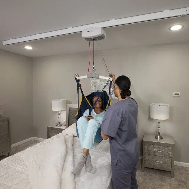 A woman is being lifted in a sling by a nurse