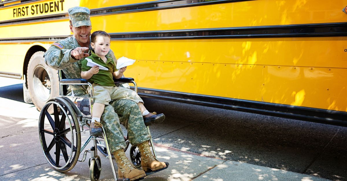 Veteran in a wheelchair holding a child on his lap as they read a heartfelt Veterans Day letter together.