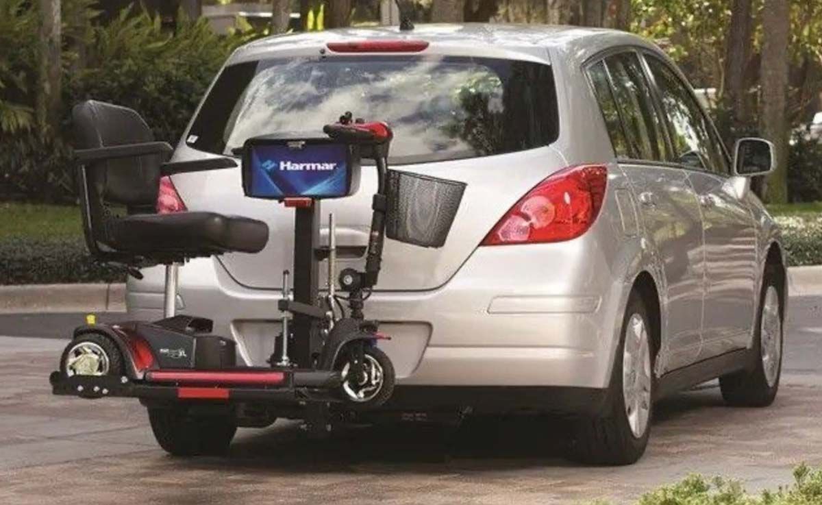 A mobility scooter is attached to the back of a van on a wheelchair lift for van.