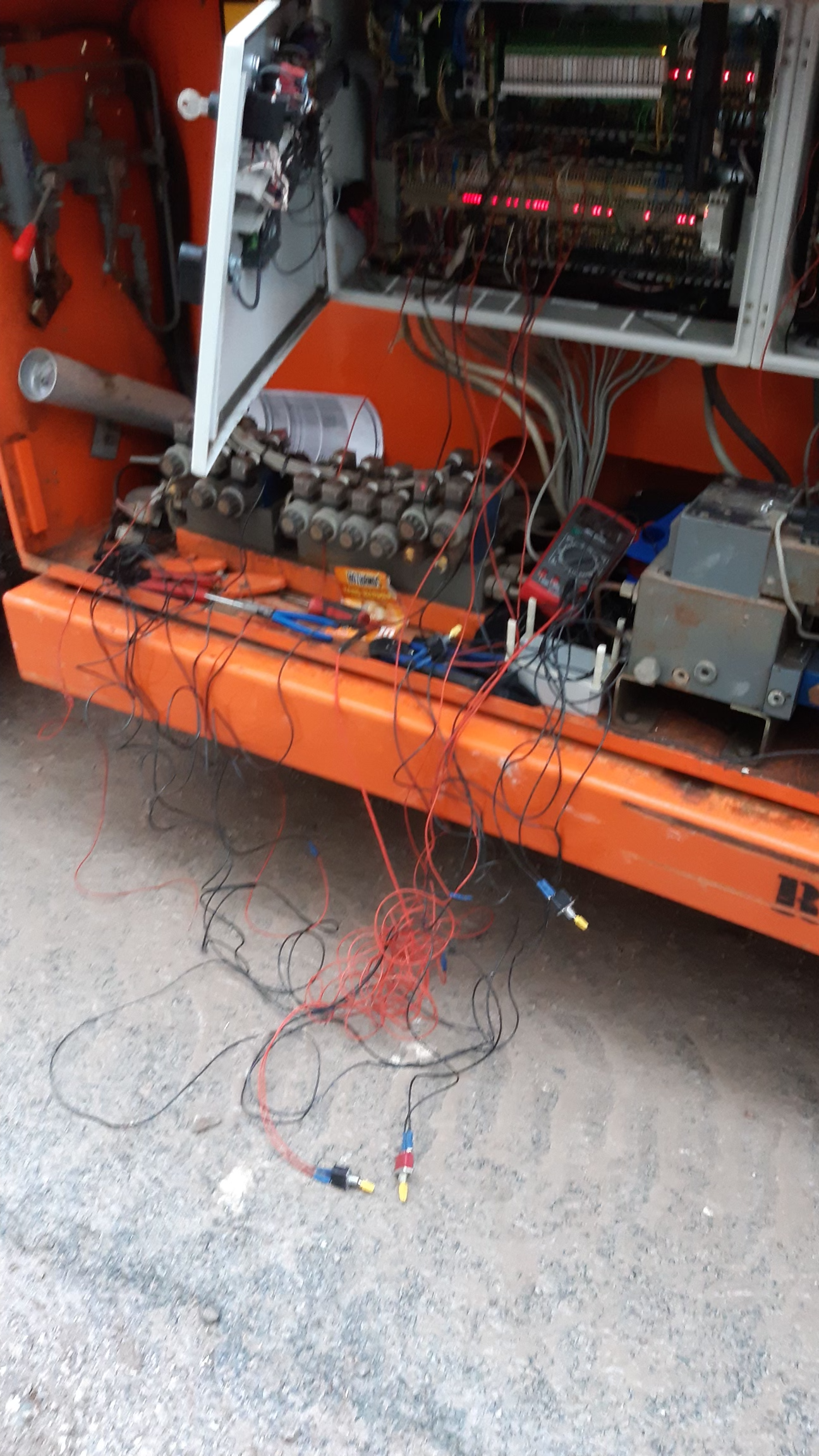 Orange machine with open panel, displaying wires, circuits, and machinery components.