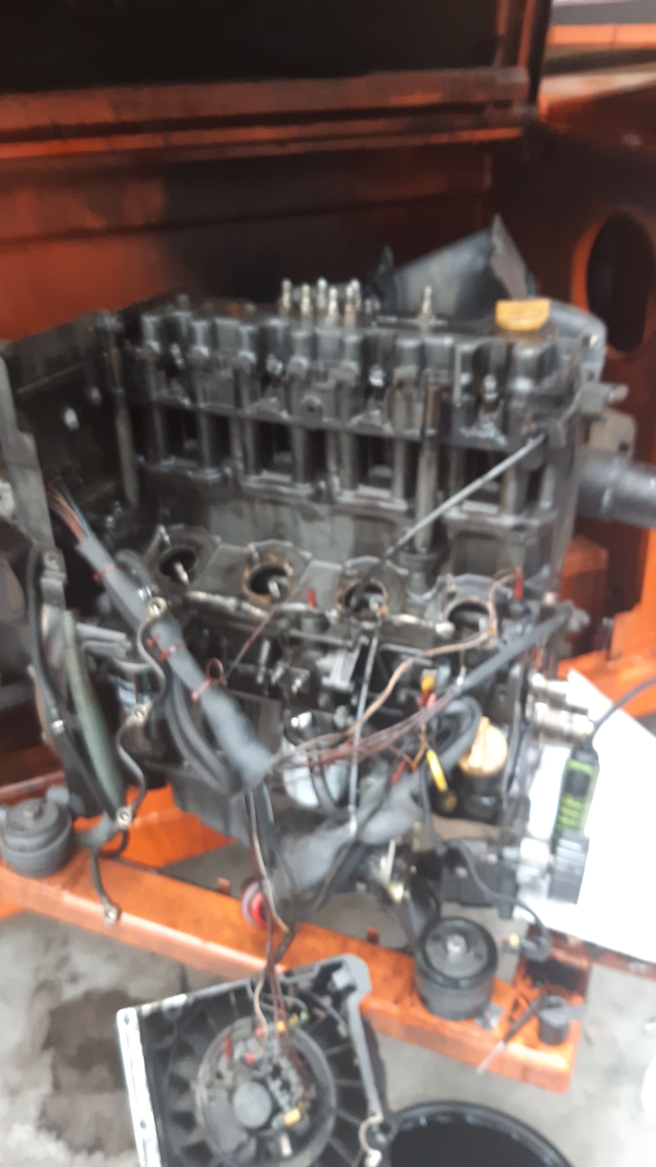 Black engine on an orange stand, radiator and other parts nearby, likely undergoing repair.