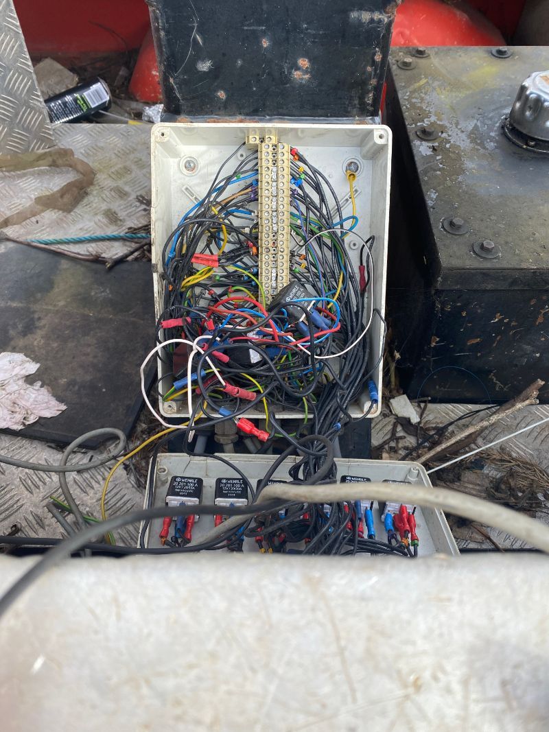 Electrical wiring in an open box, filled with wires and connectors, inside of a boat.