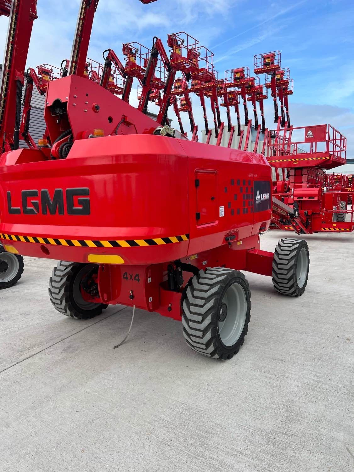 Red LGMG aerial work platform with raised arms, outdoors on concrete.