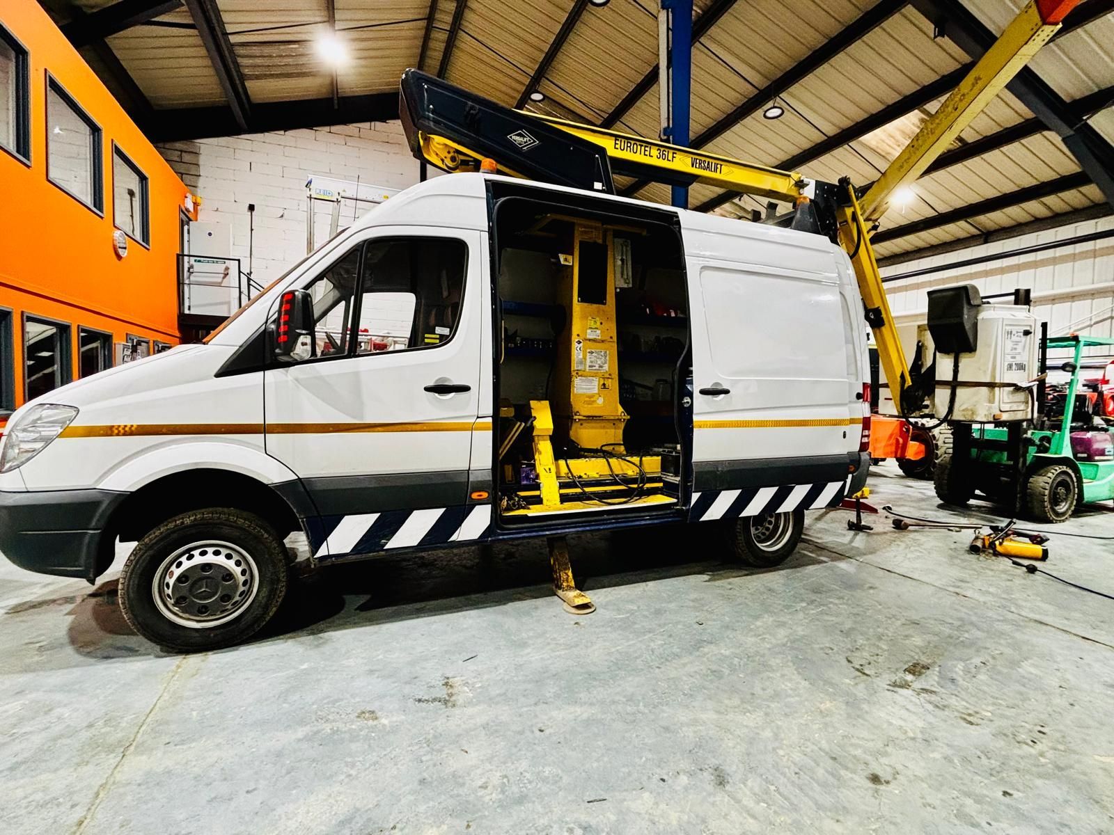 White work van with yellow crane arm extended, door open, and black and white hazard striping.