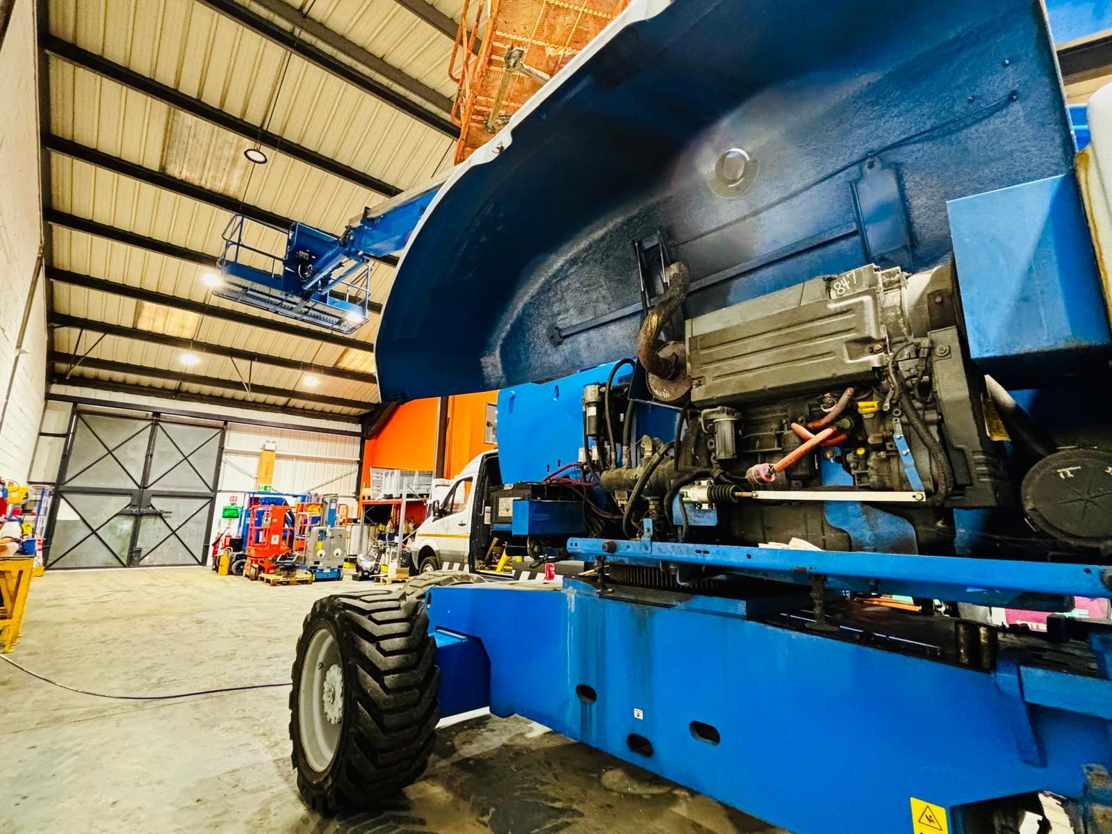 Blue industrial lift in a warehouse; engine exposed.