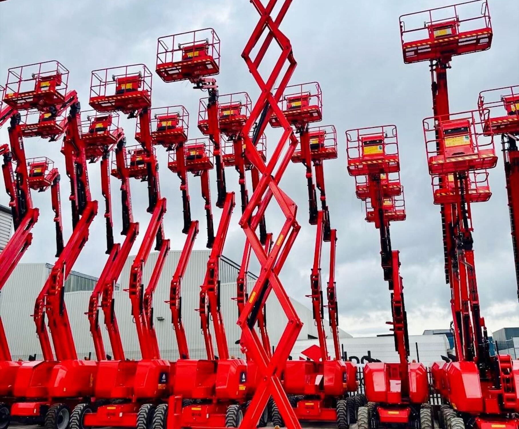 Red scissor lifts lined up outdoors.