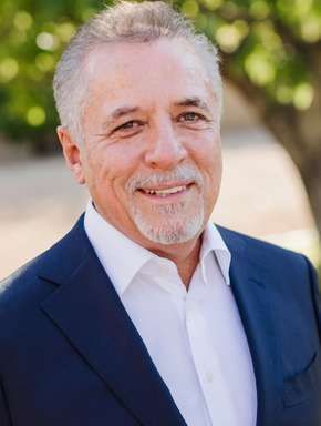 A man in a suit and white shirt is smiling for the camera.