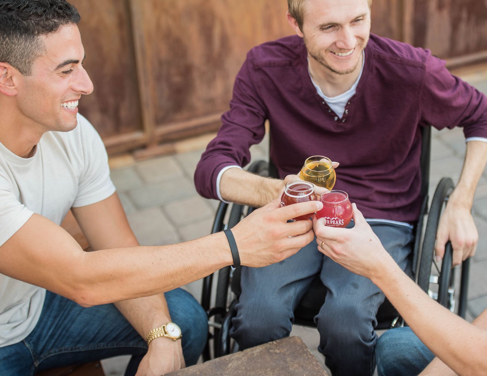 A man in a wheelchair is toasting with his friends.