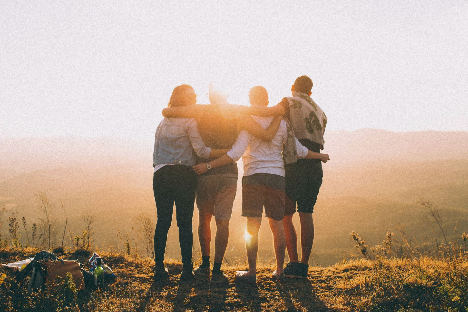A group of people are standing on top of a hill with their arms around each other.