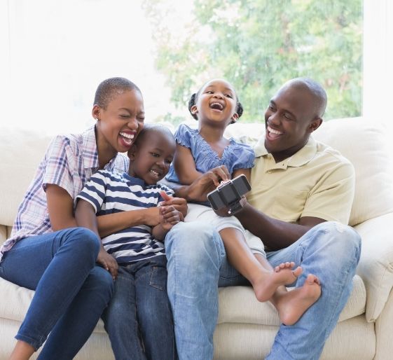 Family laughing together on a couch in a bright living room