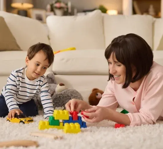 Adult and toddler playing with colorful blocks on a living room rug