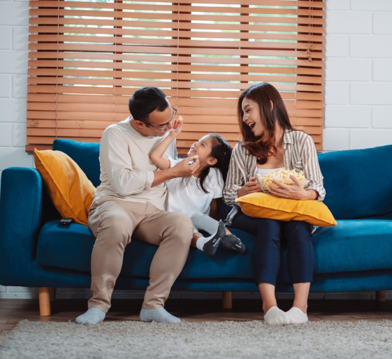 Family sitting on a blue couch, laughing together in a bright living room
