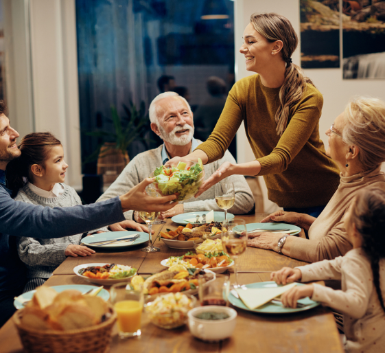 Family gathered around a table as a woman serves food in a warm dining room