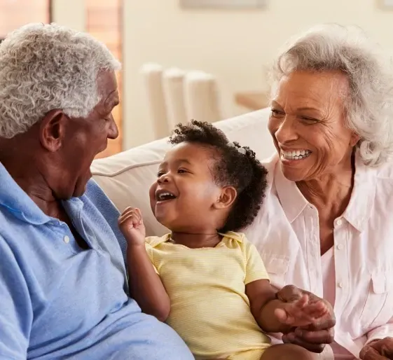 Three people smiling on a couch, sharing a warm family moment
