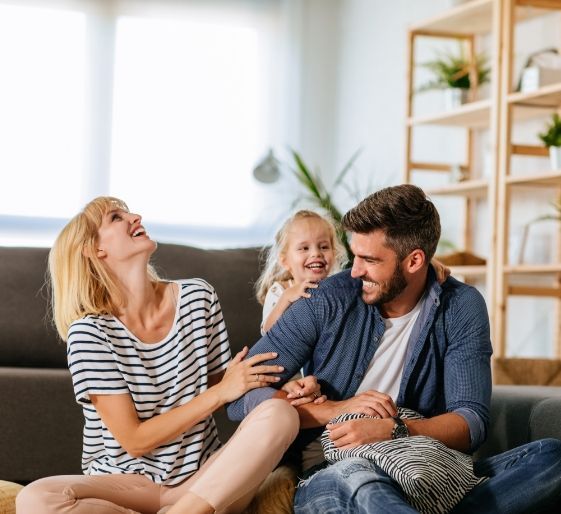 Family laughing together on a couch in a bright living room