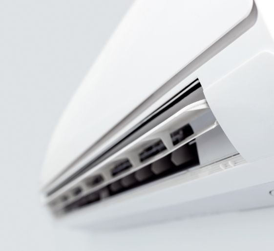 White wall-mounted air conditioner with vents open, shown close-up on a white wall