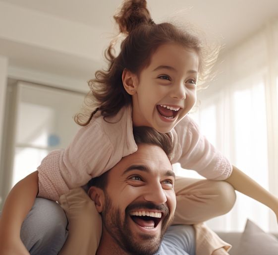 Smiling child on a man’s shoulders in a bright room, both laughing.