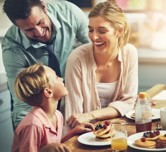 Family smiling at a table with pancakes and juice in a bright café