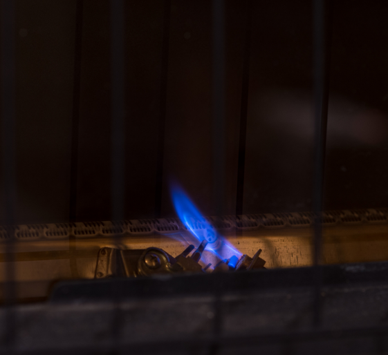 Blue flame from a gas burner behind a dark window at night