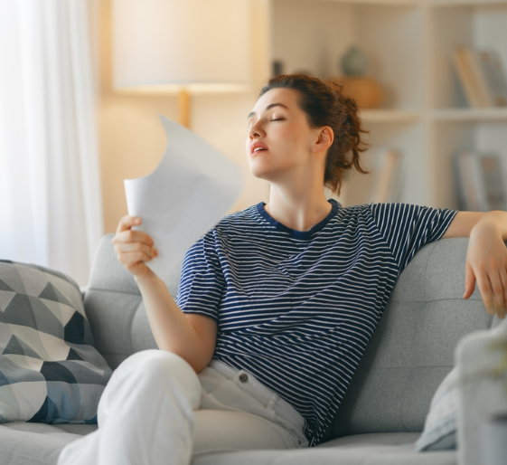 Woman on a gray couch reading a sheet of paper in a bright living room