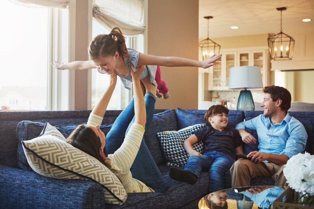 Family playing together on a blue couch in a bright living room