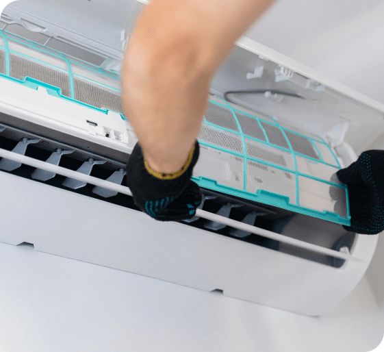 Person cleaning an air conditioner filter with a gloved hand
