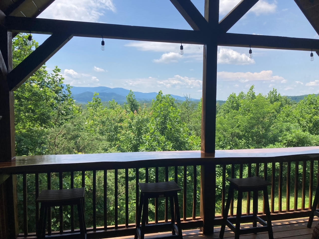 A wooden deck with a view of a forest and mountains.