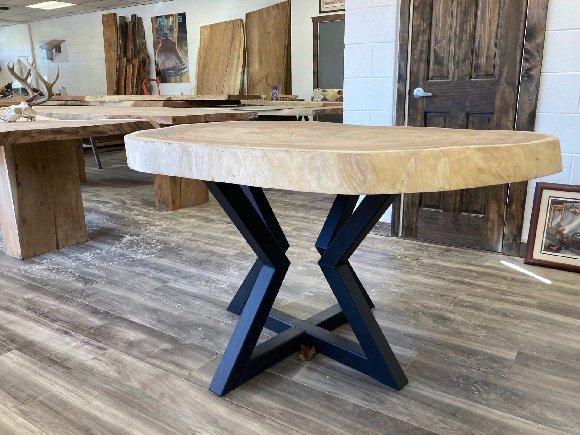 A round wooden table with a black metal base in a room.