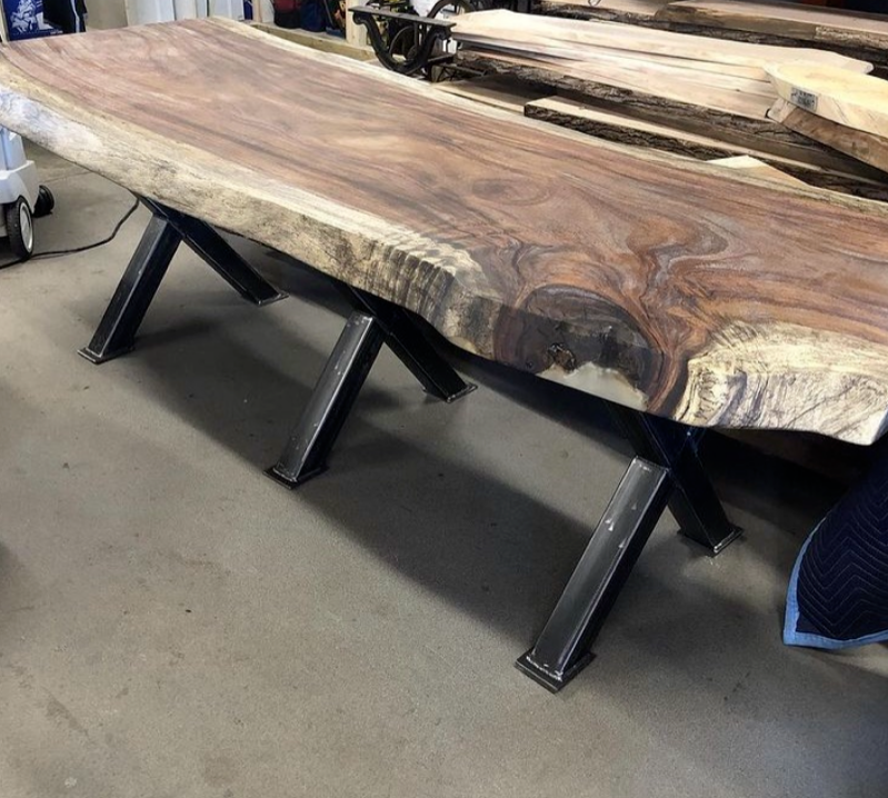 A wooden table with metal legs is sitting on a concrete floor.