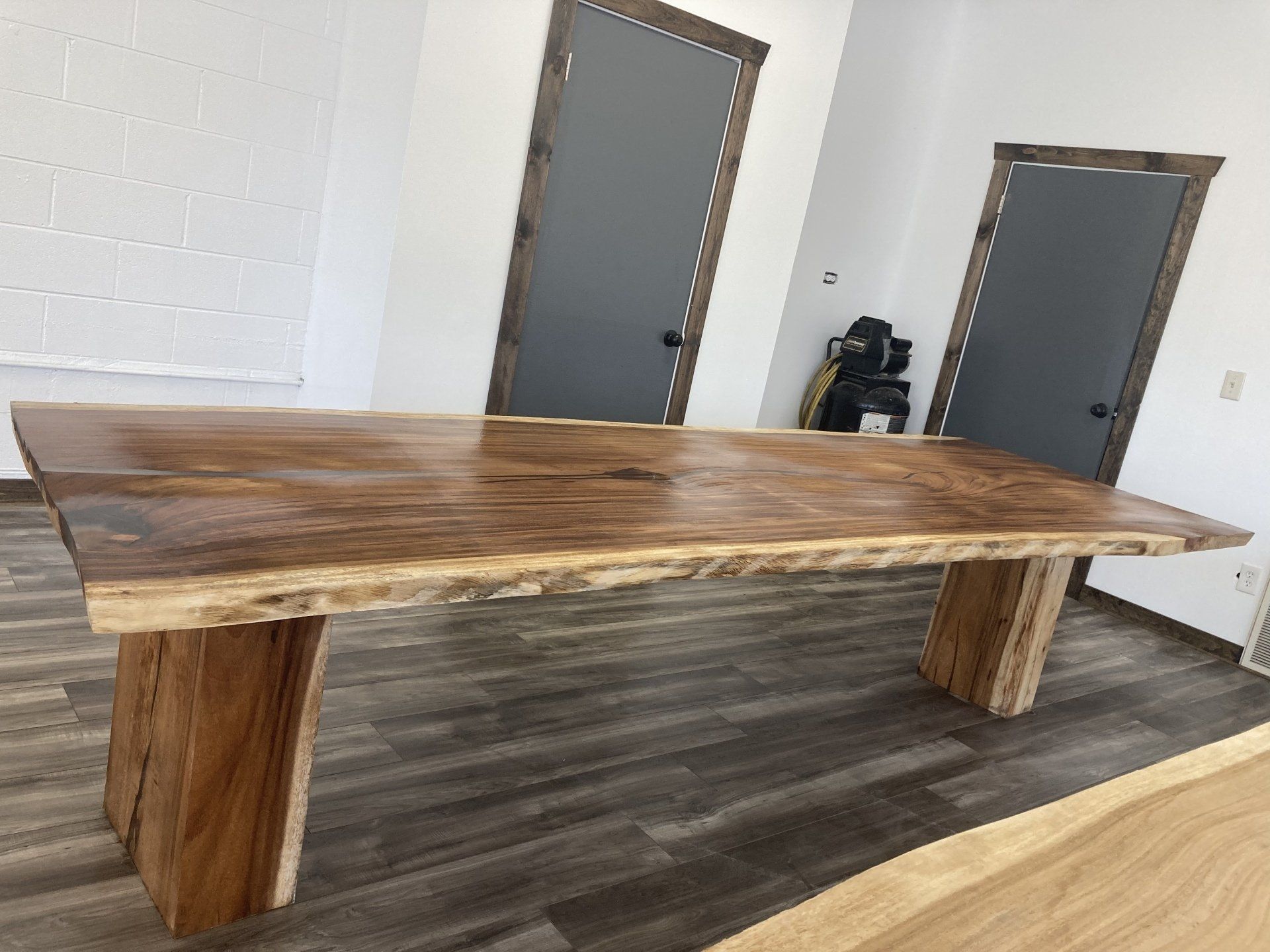 A large wooden table is sitting in a room next to two doors.