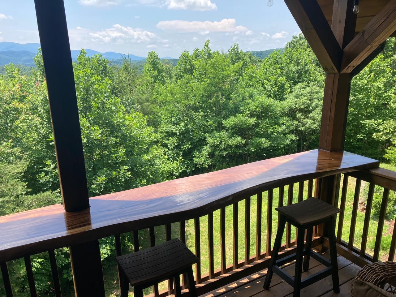 A wooden deck with a view of a forest and mountains.