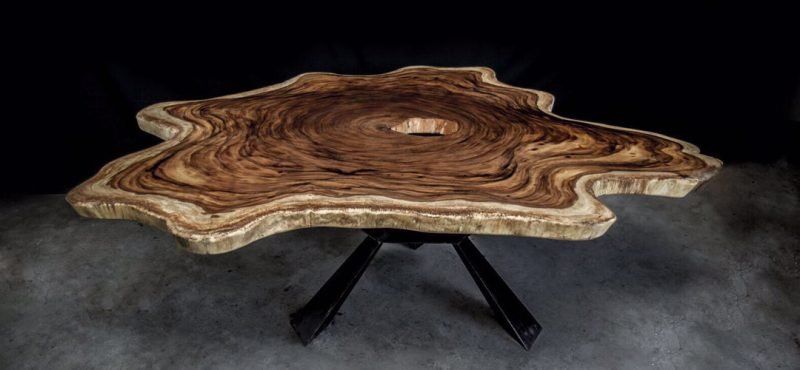 A wooden table with a hole in the middle is sitting on a concrete floor.