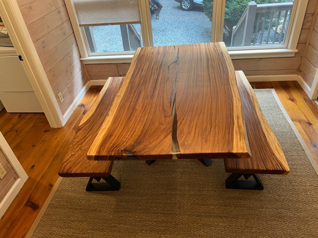 A wooden table with two benches in a room next to a window.