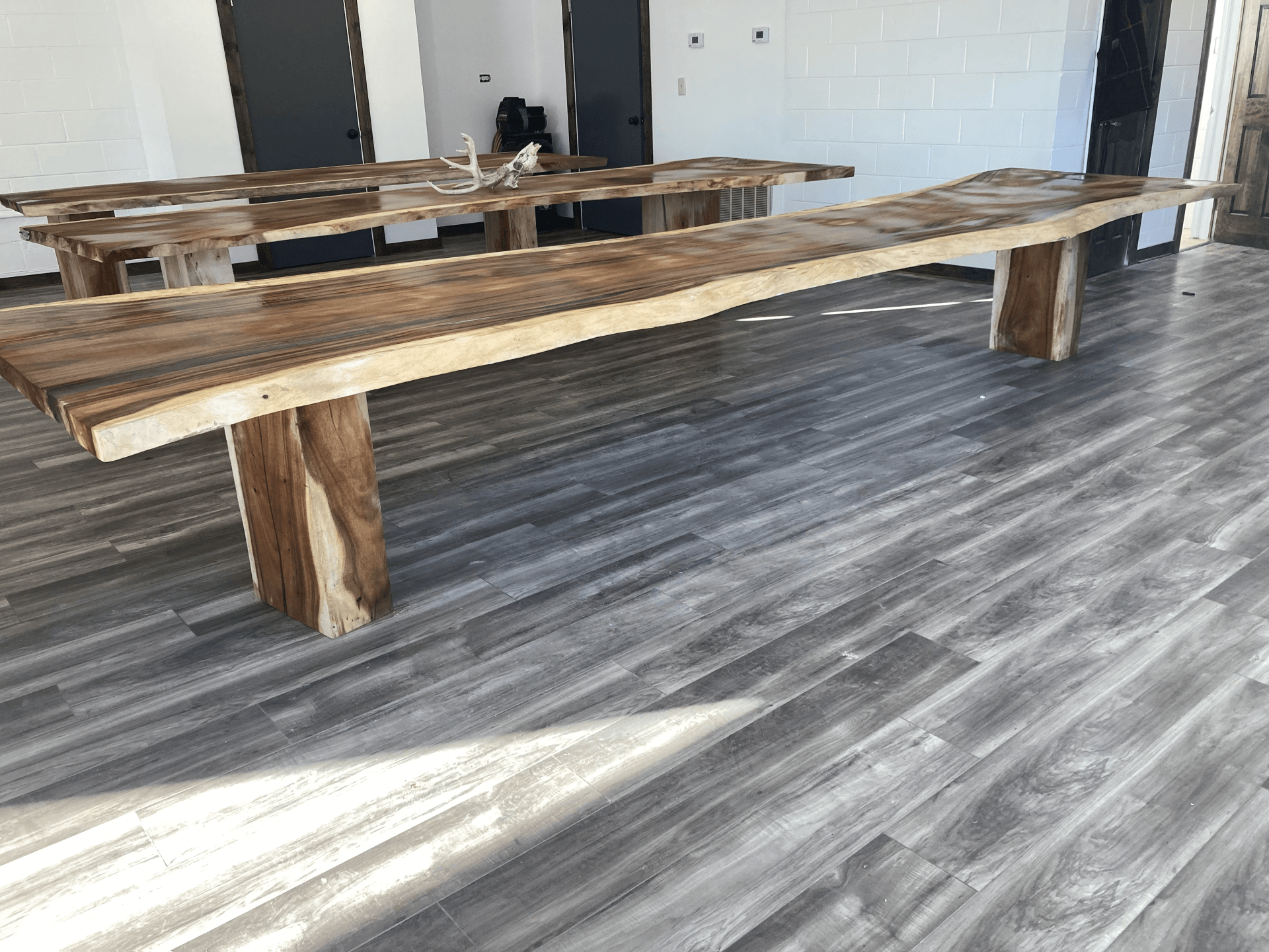 A long wooden table and benches are sitting on a wooden floor in a room.