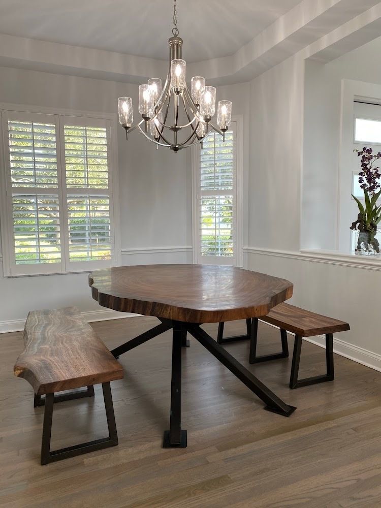 A dining room with a wooden table and benches and a chandelier.