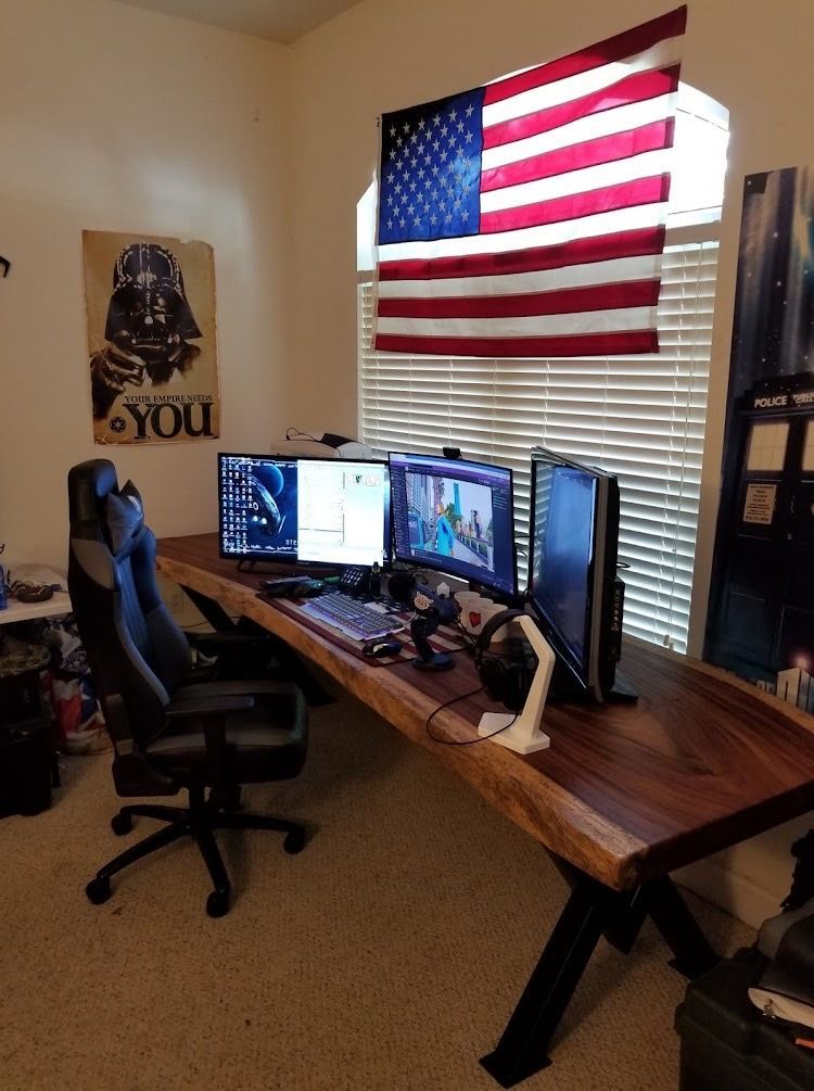 A computer desk with two monitors and a chair in a room.