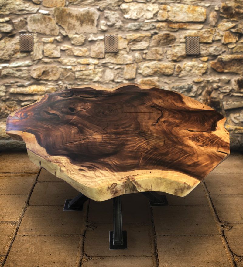A wooden table is sitting on a tiled floor in front of a stone wall.