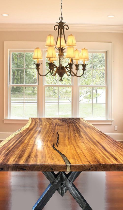 A dining room with a large wooden table and a chandelier hanging from the ceiling.