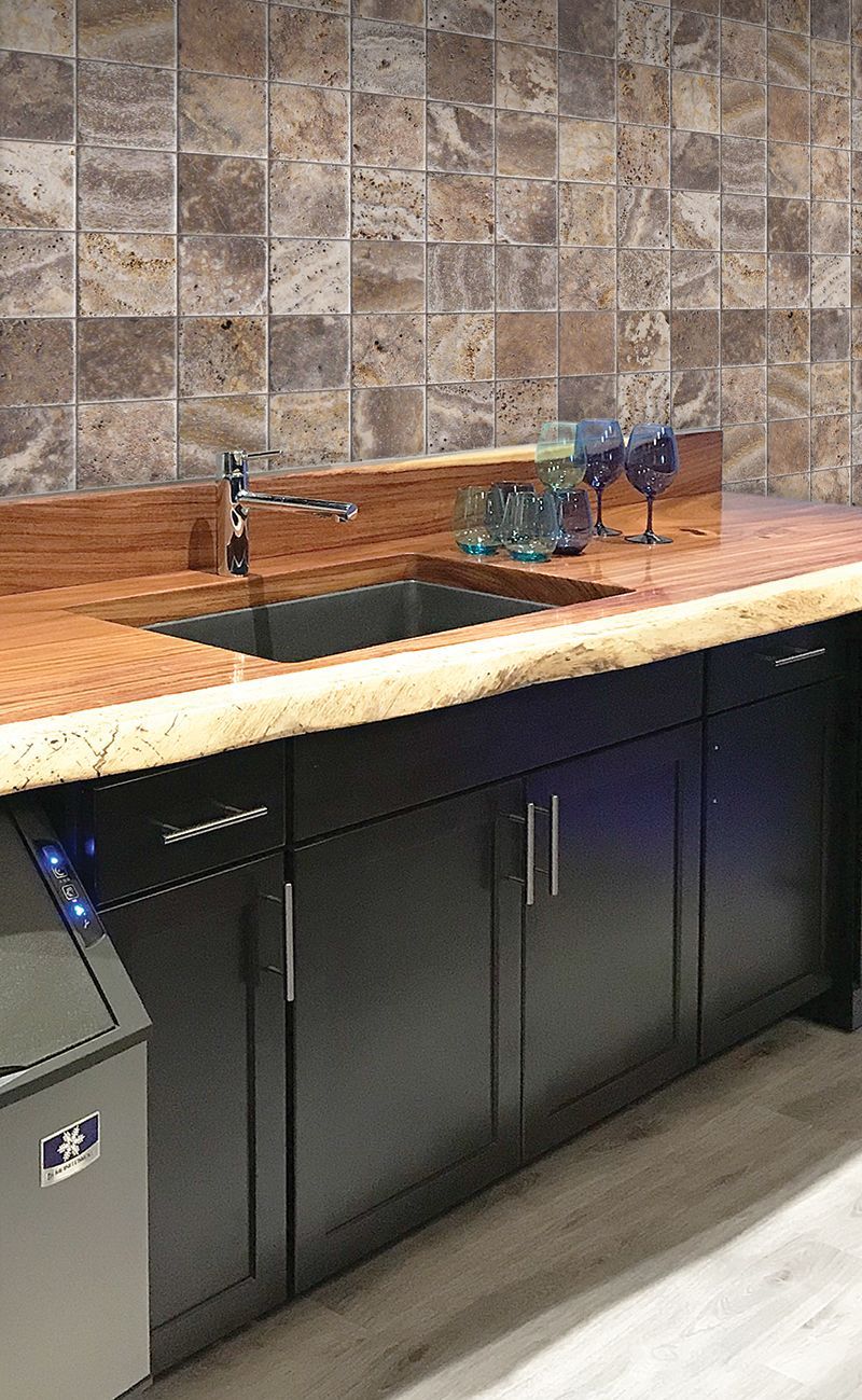 A kitchen with a sink , cabinets , and a trash can.