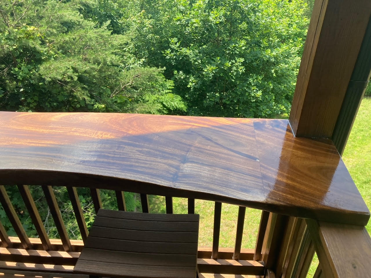 A wooden deck with a table and chairs and trees in the background.