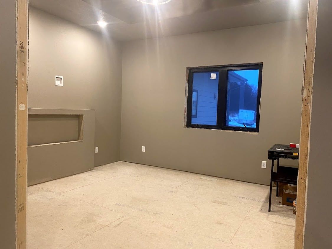 Empty beige room with carpet, window, and small table against the wall