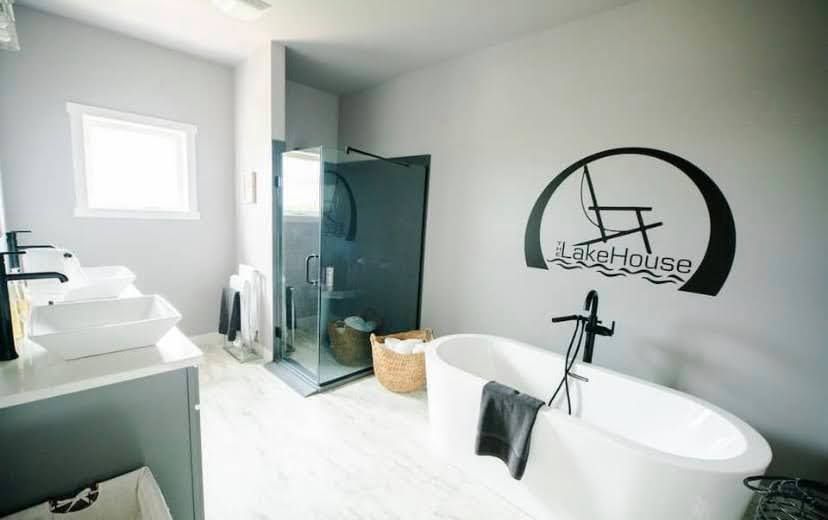 Modern bathroom with freestanding tub, glass shower, white vanity, and black wall decor