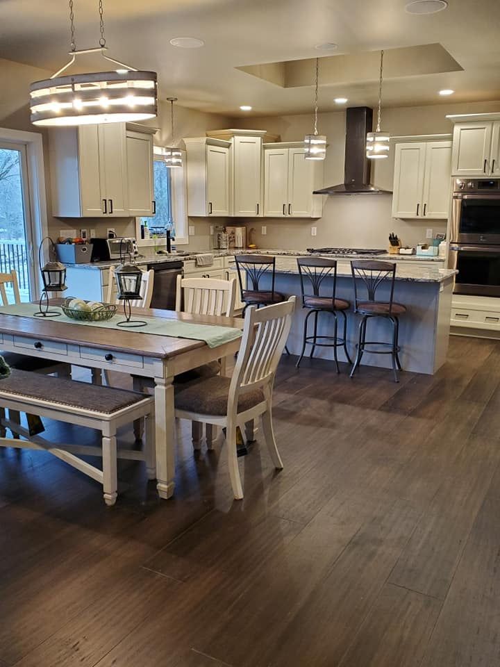 Open-concept kitchen and dining area with white cabinets, island stools, and dark wood floors