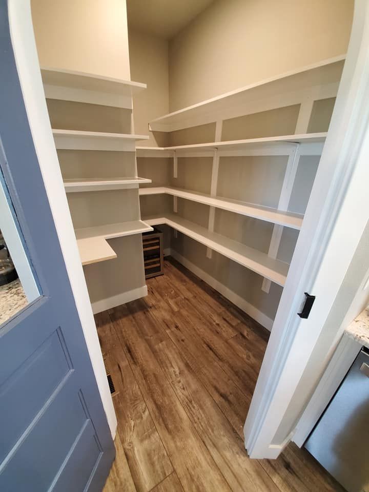 Empty walk-in closet with white built-in shelves and wood flooring, viewed from the doorway
