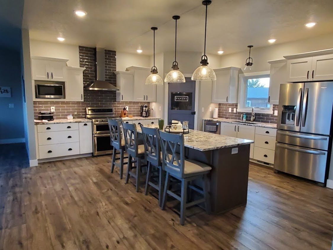 Modern open kitchen with island, pendant lights, stainless appliances, and wood flooring