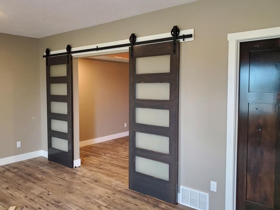 Sliding barn doors opening to a room with wood floors and beige walls