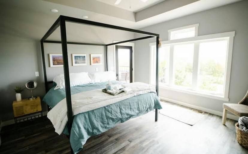 Modern bedroom with black canopy bed, teal bedding, and bright window light