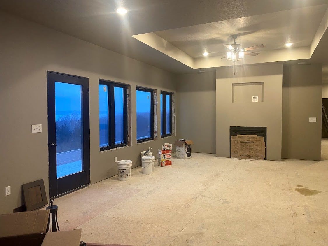 Empty living room with beige carpet, dark windows, a fireplace, and recessed ceiling lights.