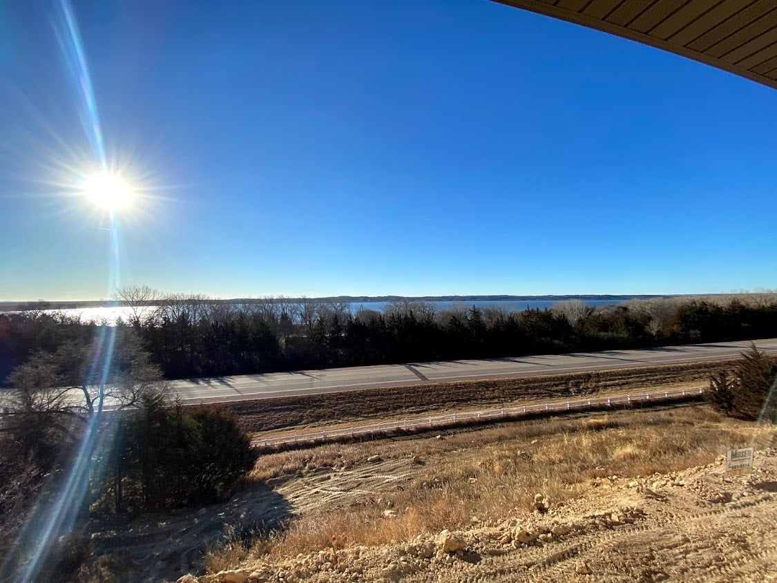 Sunlit snowy field with trees on the horizon under a bright blue sky